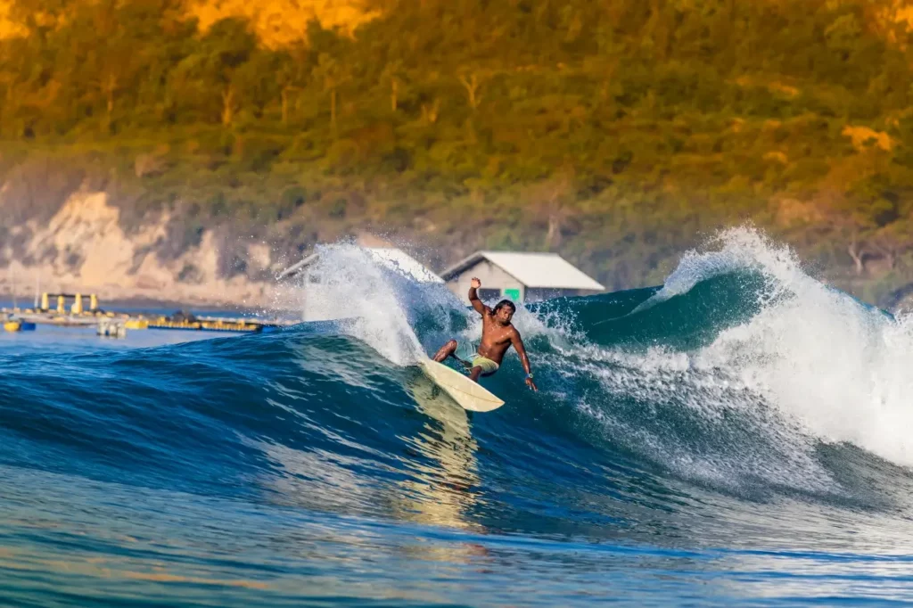 An enthusiastic surfer catches a robust wave, exemplifying the exhilarating Sumbawa surf experience